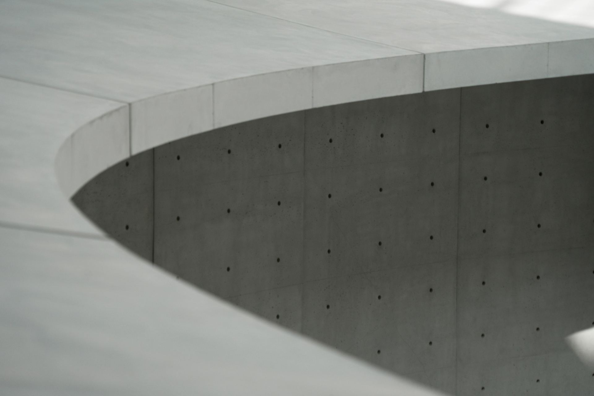 Curved concrete wall with tie holes in soft light